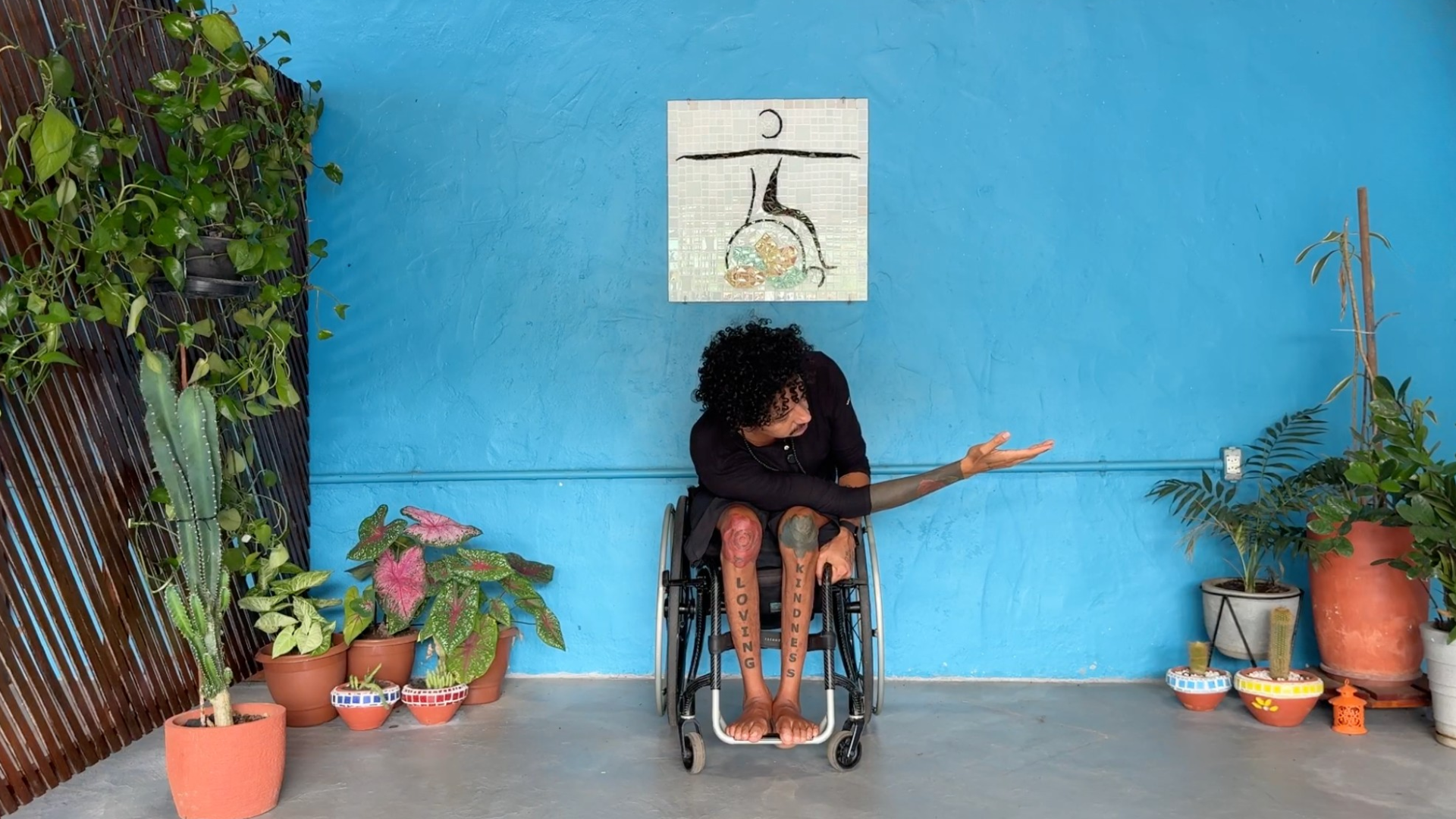 Man leading a wheelchair yoga class and reaching one arm underneath his chest toward the right