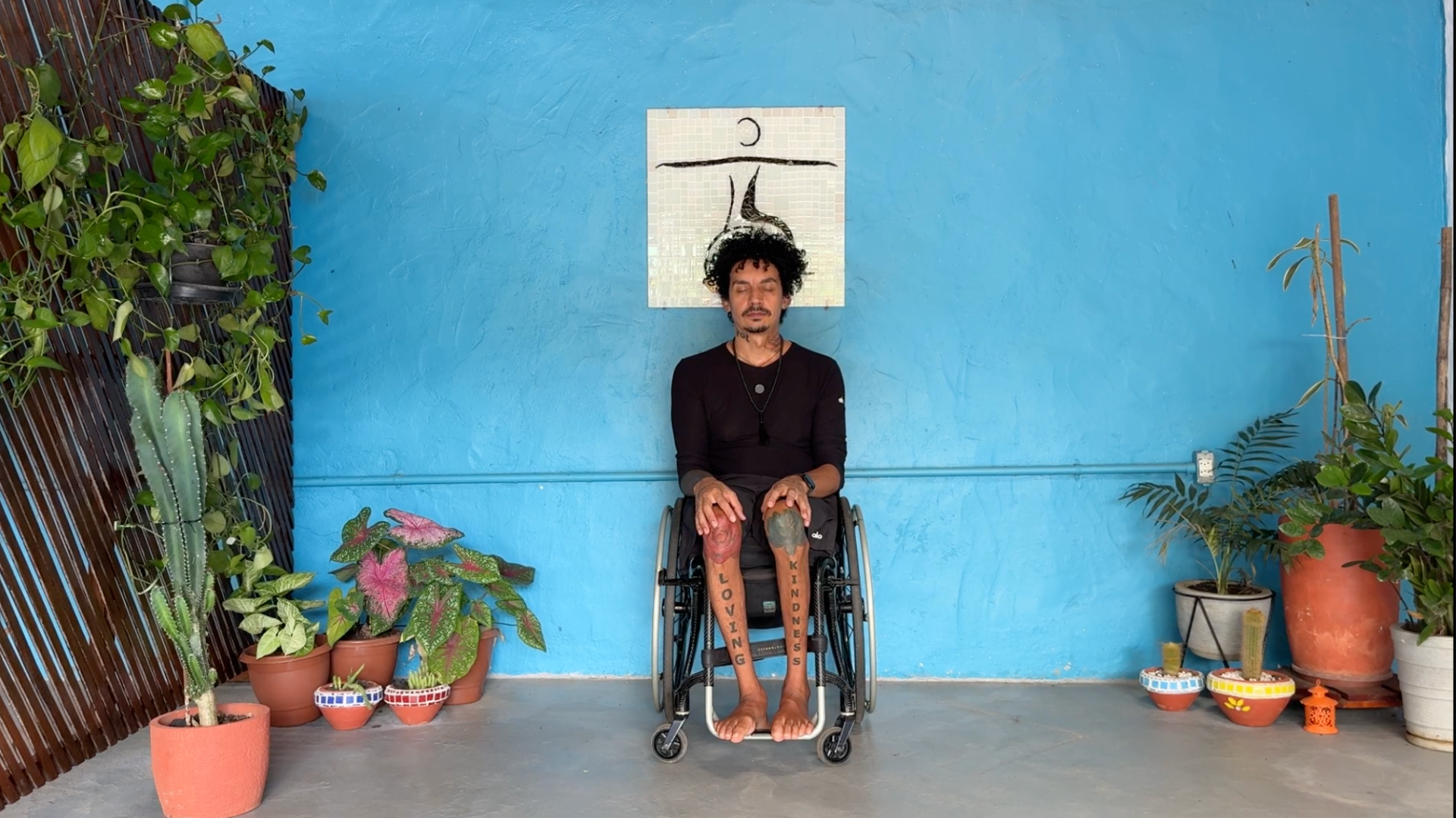 A yoga teacher sitting in a wheelchair on a yoga chair version of Mountain or Tadasana