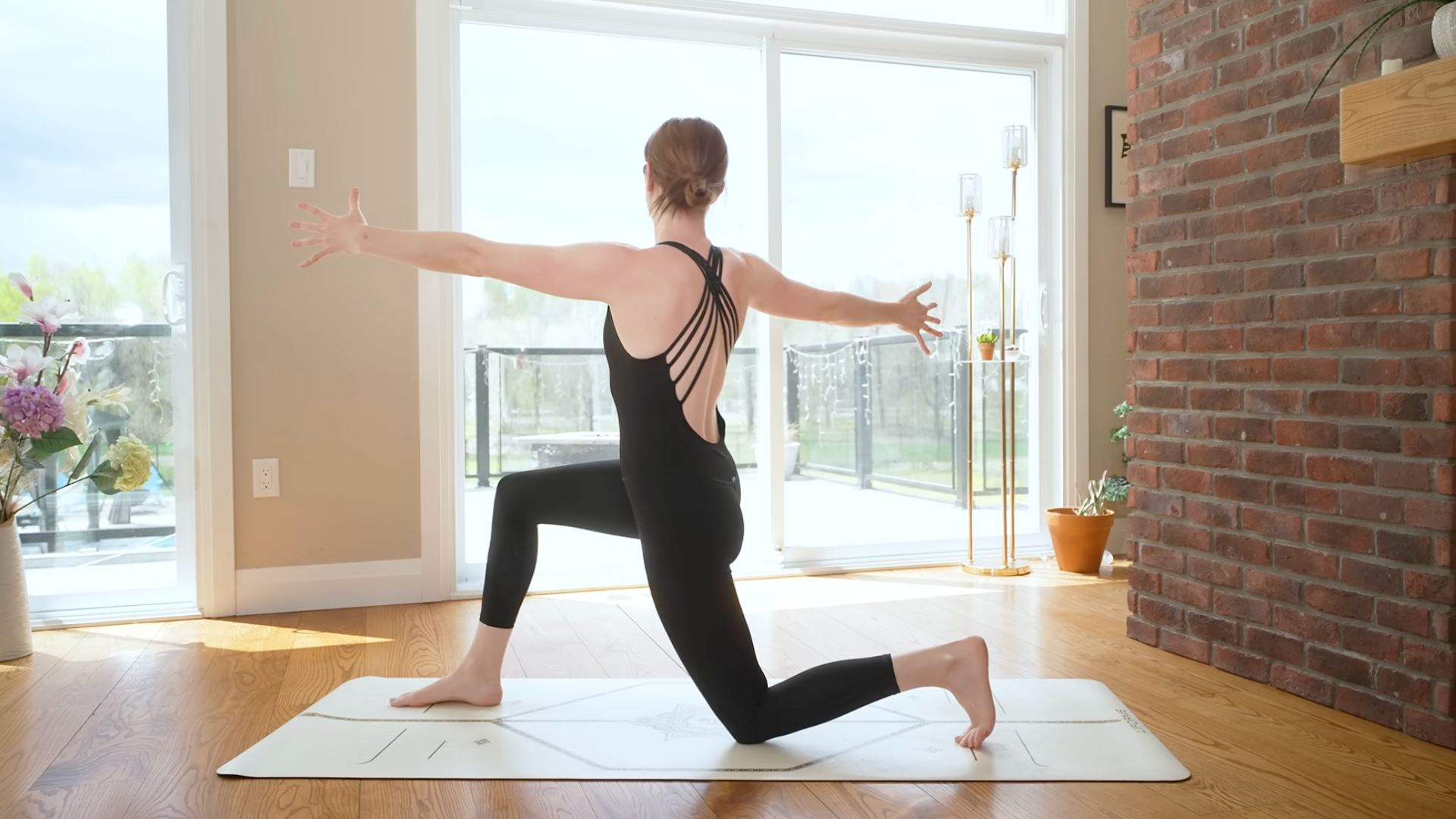 Woman kneels in Low Lunge as she turns to the right with her arms extended straight out from the shoulders