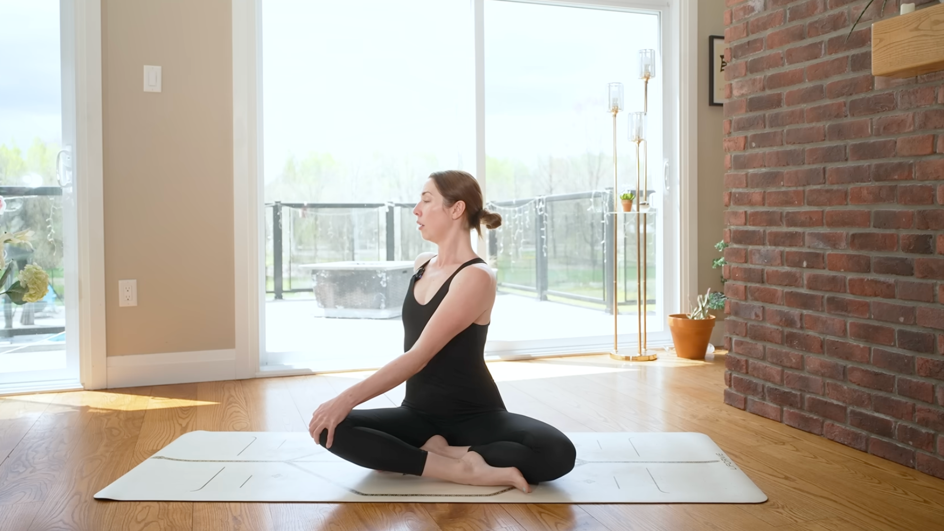 A woman sits on a yoga mat and turns to her right