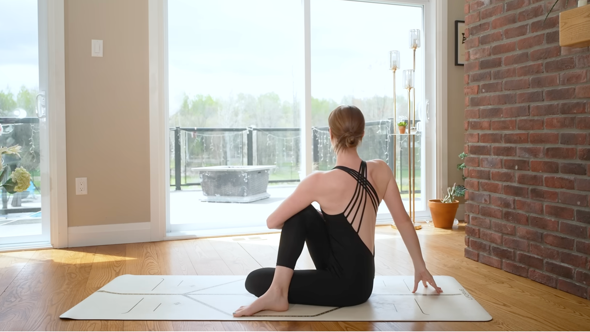 A woman sits and turns to the right in a version of Ardha Matysendrasana