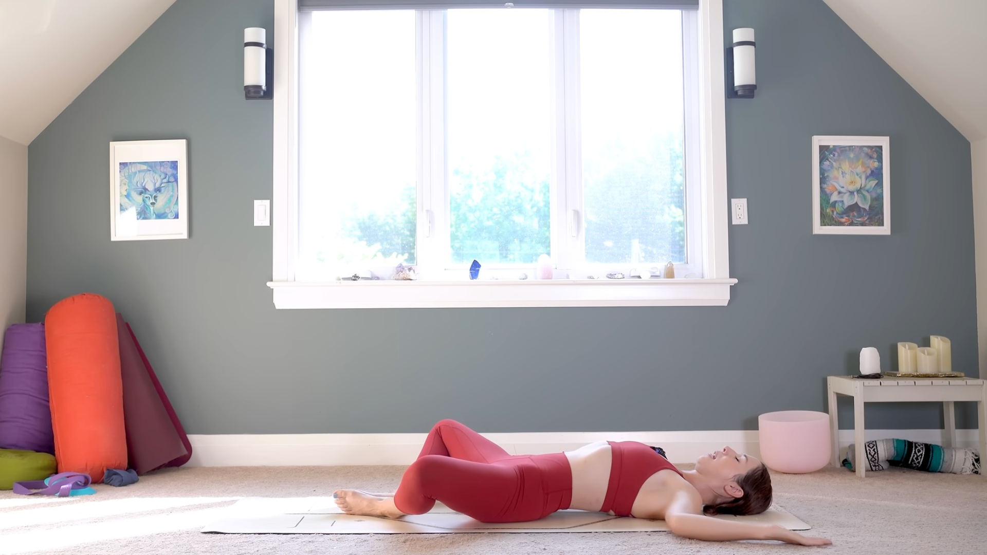 Woman lying on her back on a yoga mat in Reclining Bound Angle or Supta Baddha Konasana with cactus arms