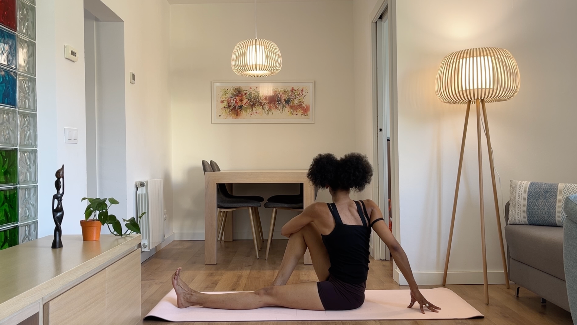 A person sitting on a mat with one leg extended straight and the other bent with the foot flat on the floor, twisting their torso toward the bent knee and wrapping the opposite arm around it.