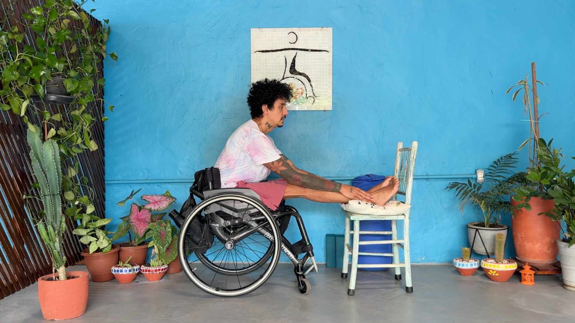 Yoga teacher seated in a wheelchair and leaning forward in a Seated Forward Bend during an accessible yoga class