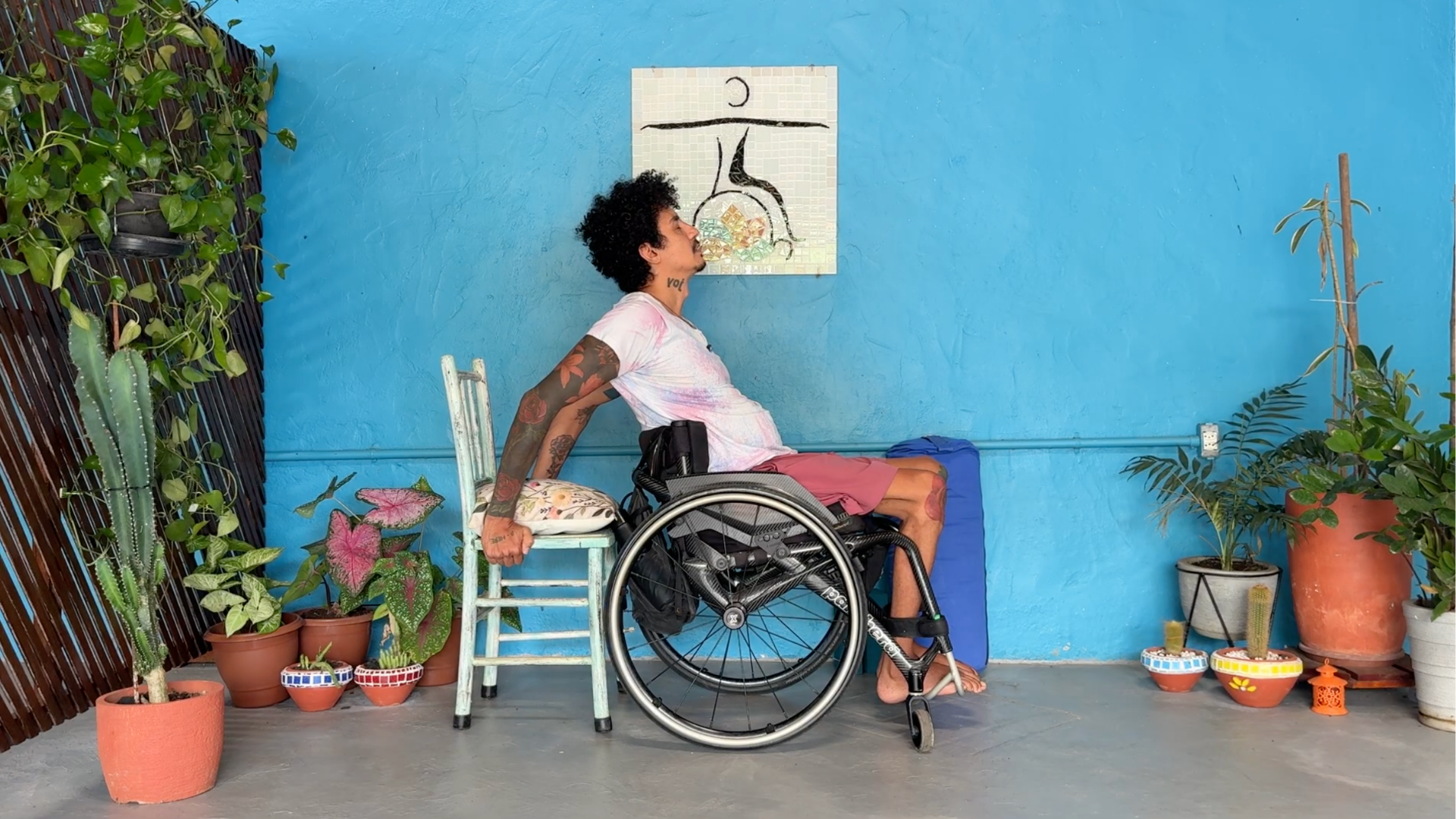 Accessible yoga teacher Rodrigo Souza leading a wheelchair yoga class and teaching the backbend known as Camel with a second chair