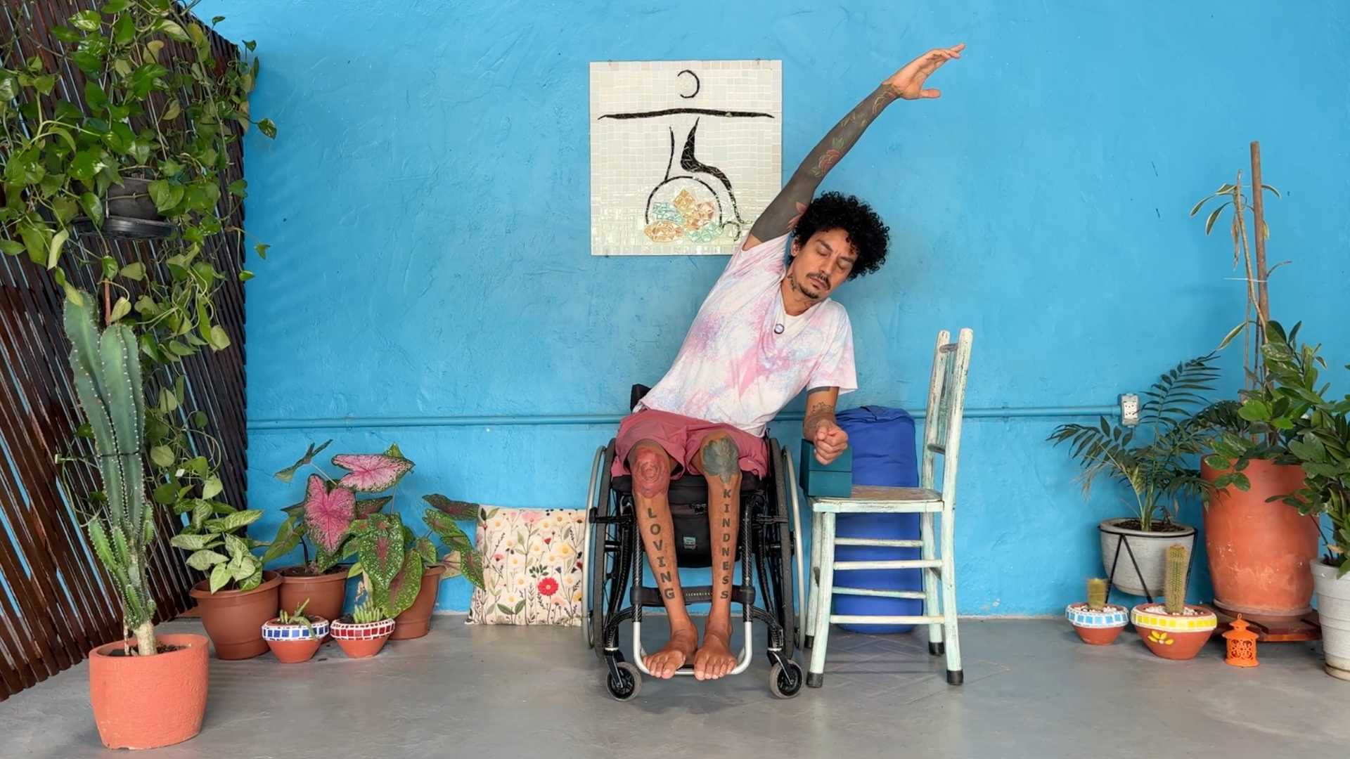 Man sitting in a wheelchair practicing side stretches by leaning one arm overhead