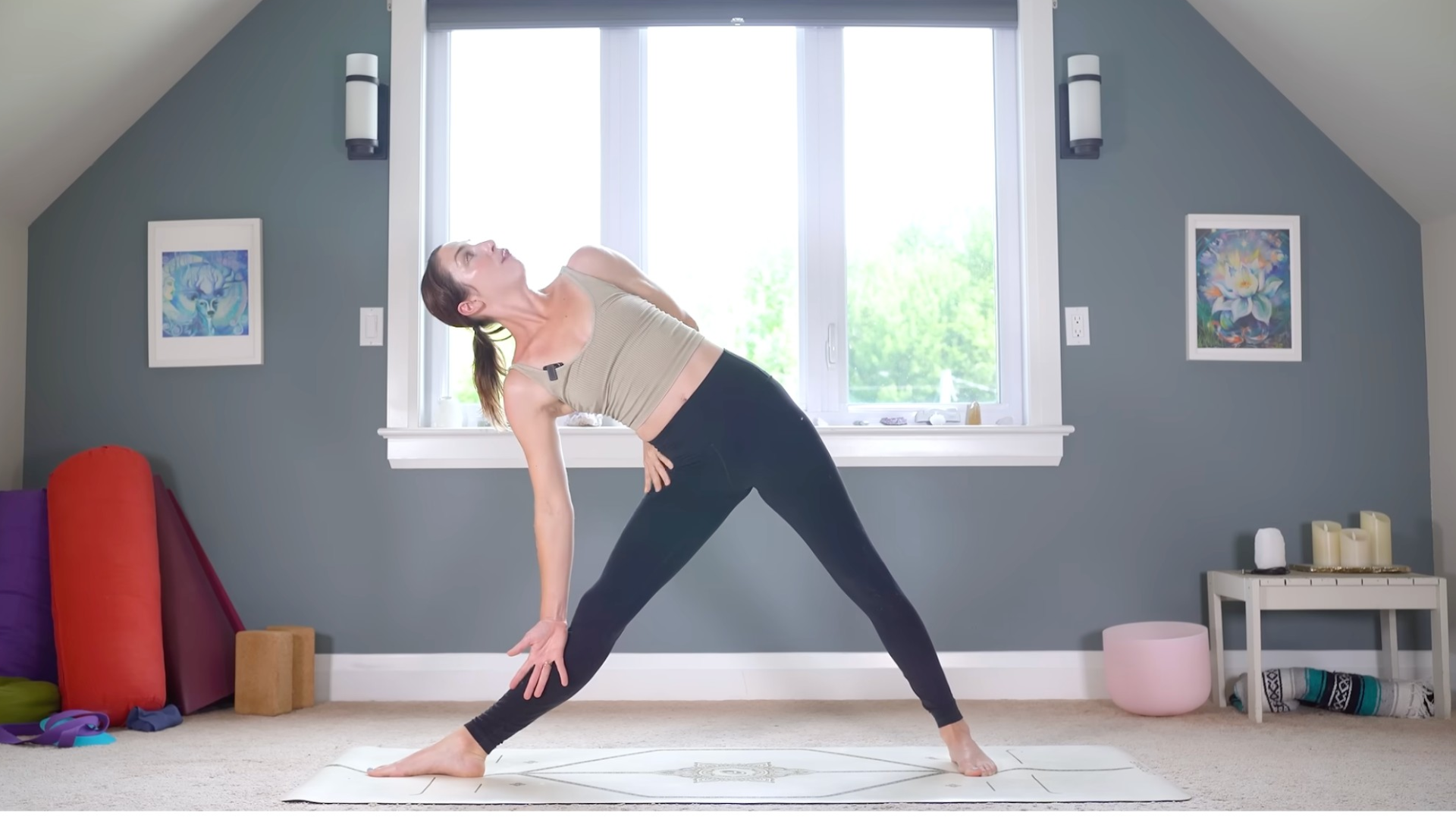 Yoga With Kassandra taking a half bind with her top arm behind her back in the yoga pose Trikonasa or Triangle 