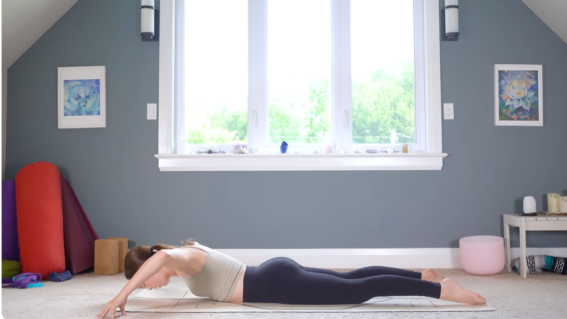 Woman doing a full-body stretch while lying on a yoga mat with her fingertips on the mat