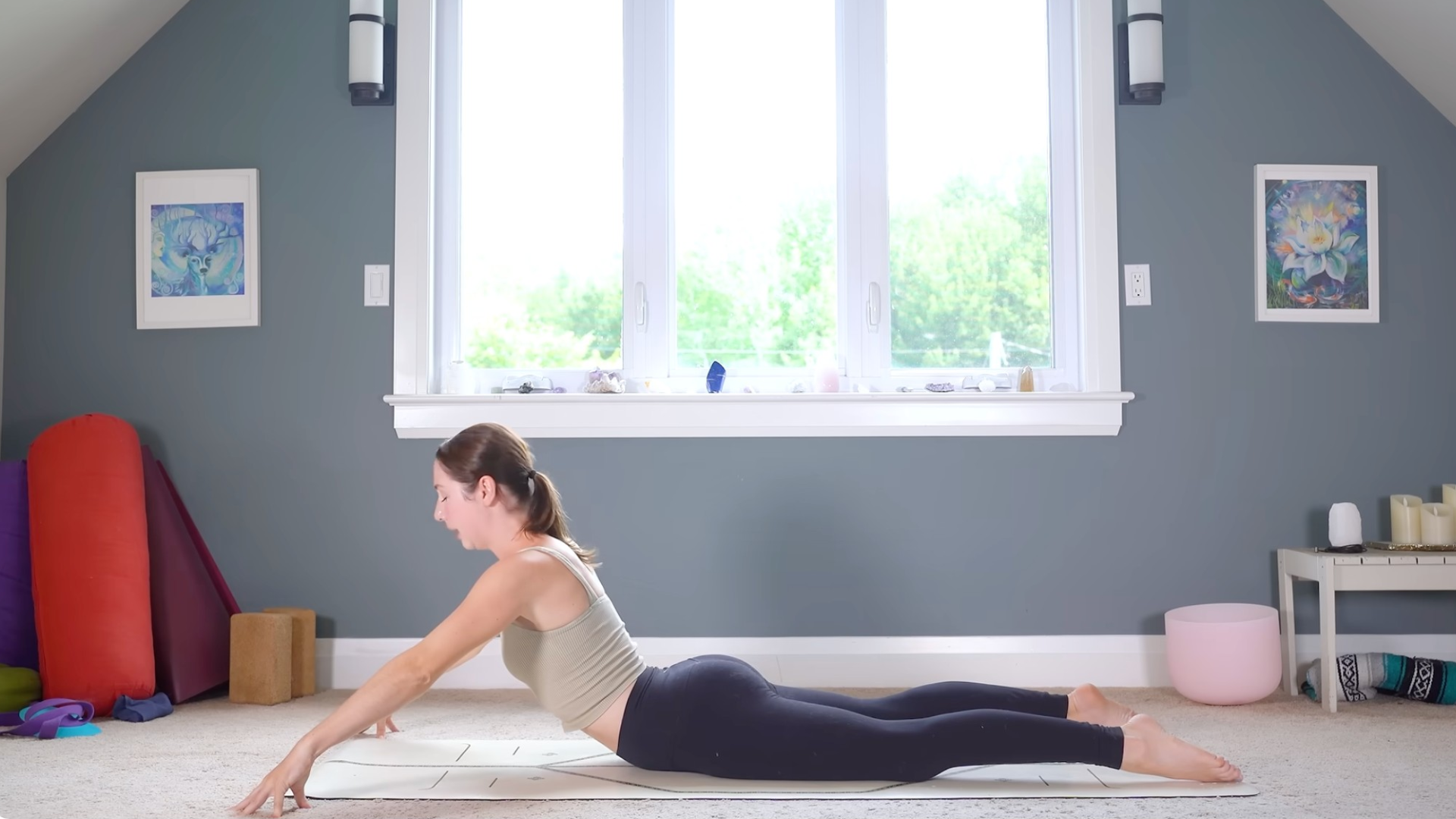 Woman lying on her belly on a yoga mat and lifting her chest into Cobra or Bhujangasana