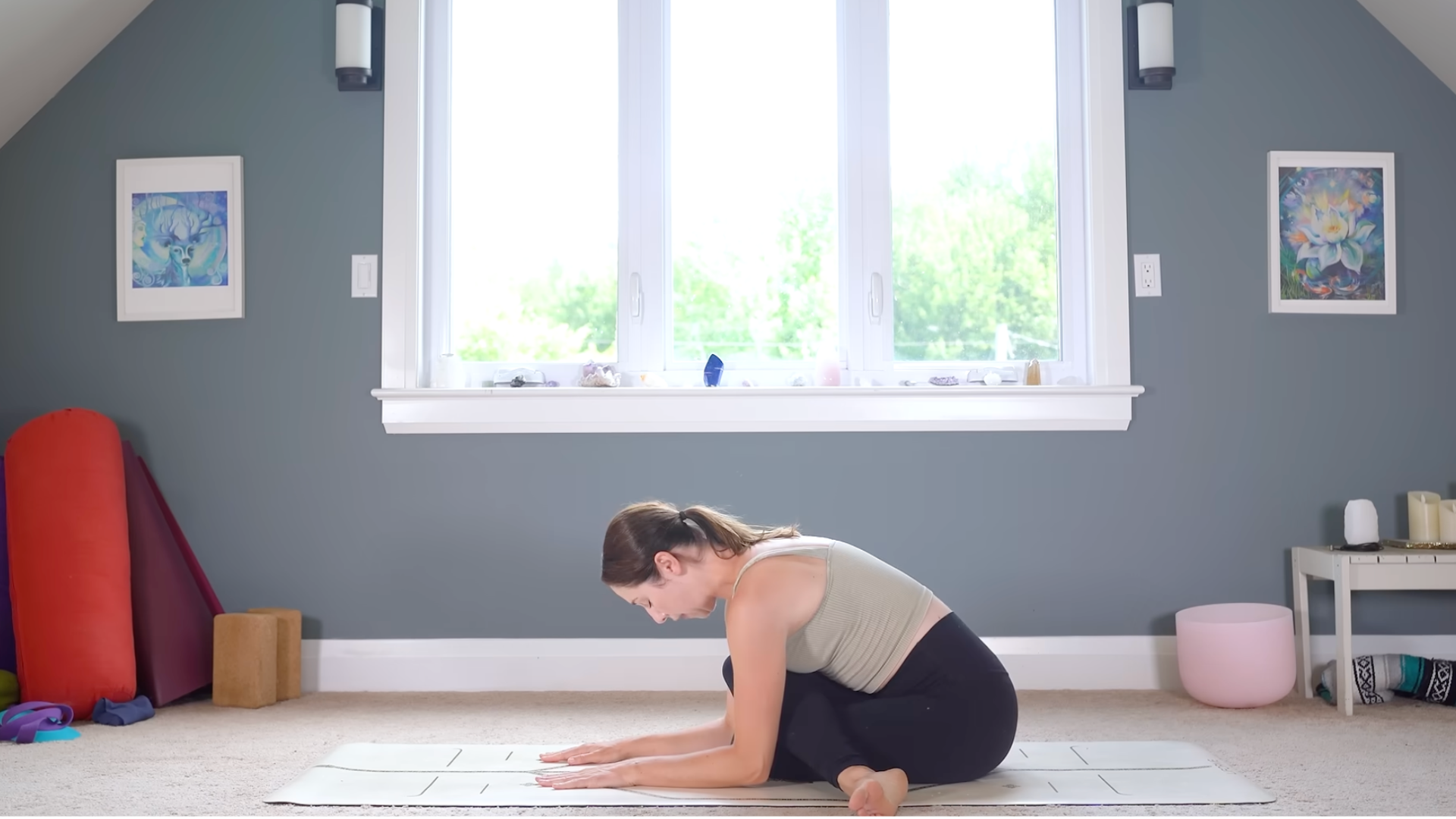 Woman sitting with her legs crossed in Cow Face or Gomukhasana during a yoga routine for a full body stretch