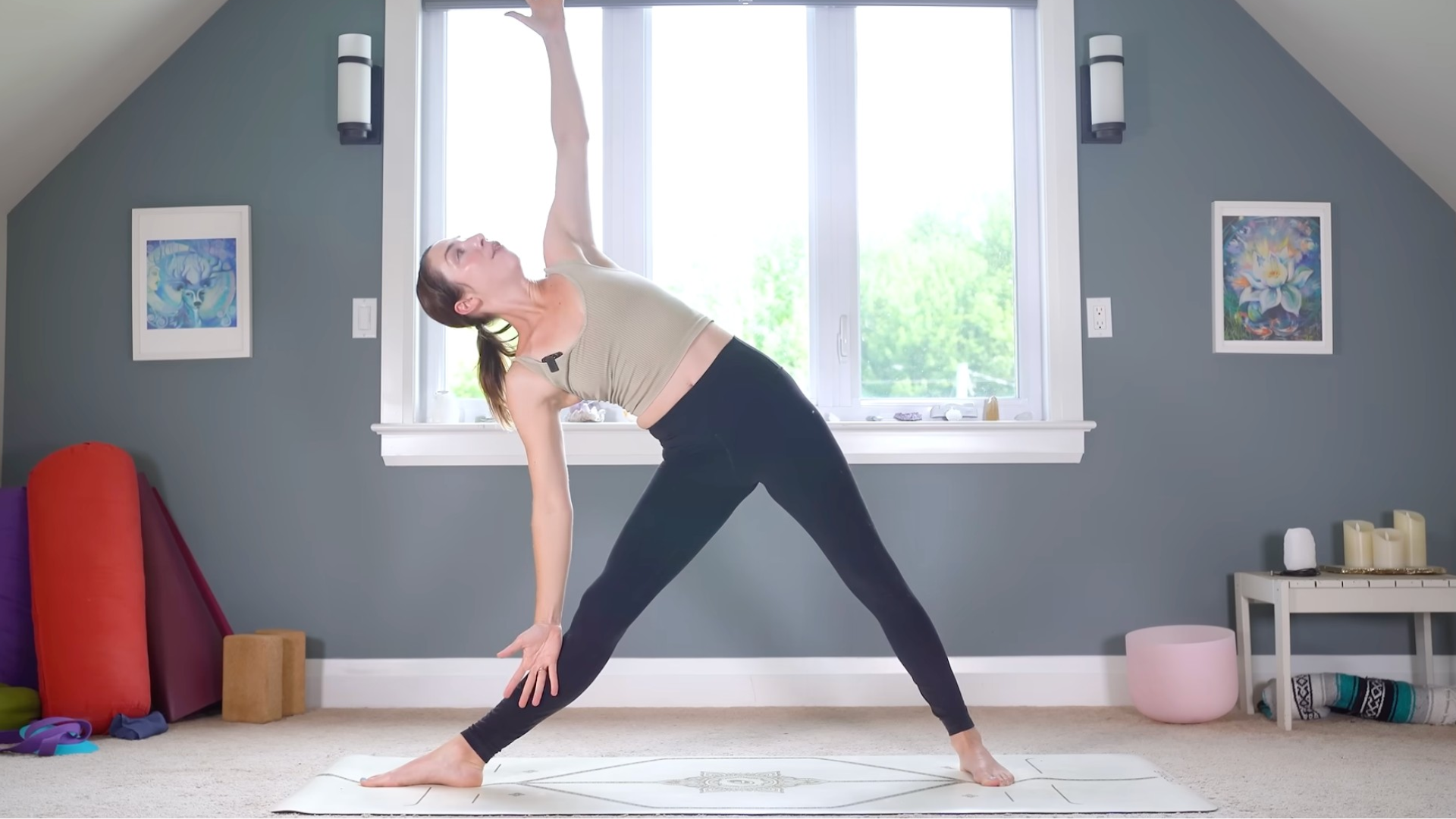 Woman in Triangle or Trikonasana with her legs straight and her head turned toward her arm reaching toward the ceiling