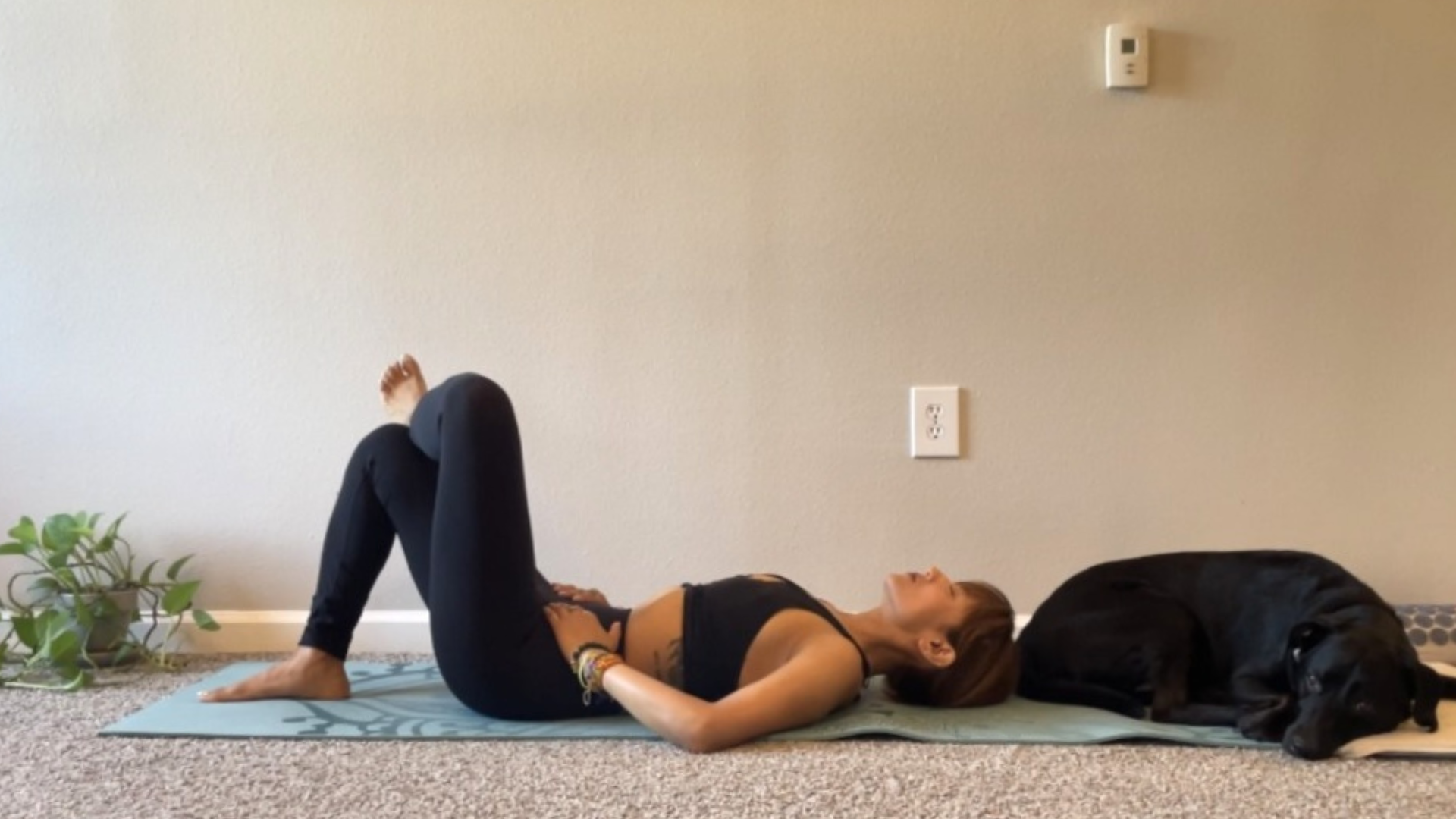 Woman lying on her back on a yoga mat in a Reclined Figure 4 or Reclined pigeon pose