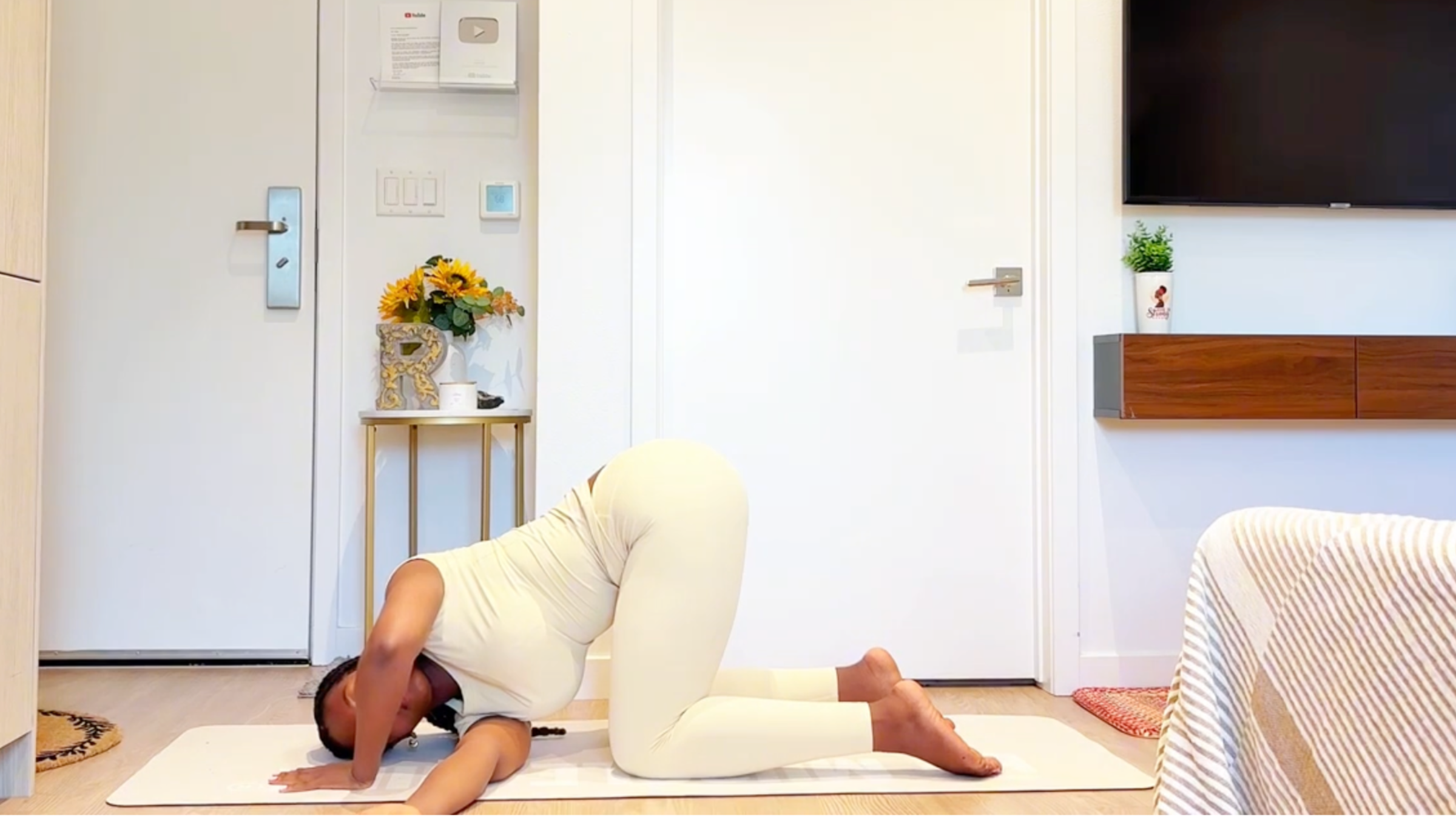 Yoga instructor Ramoni Overton doing Thread the Needle pose with one arm reached under her chest and shoulder resting on the mat.