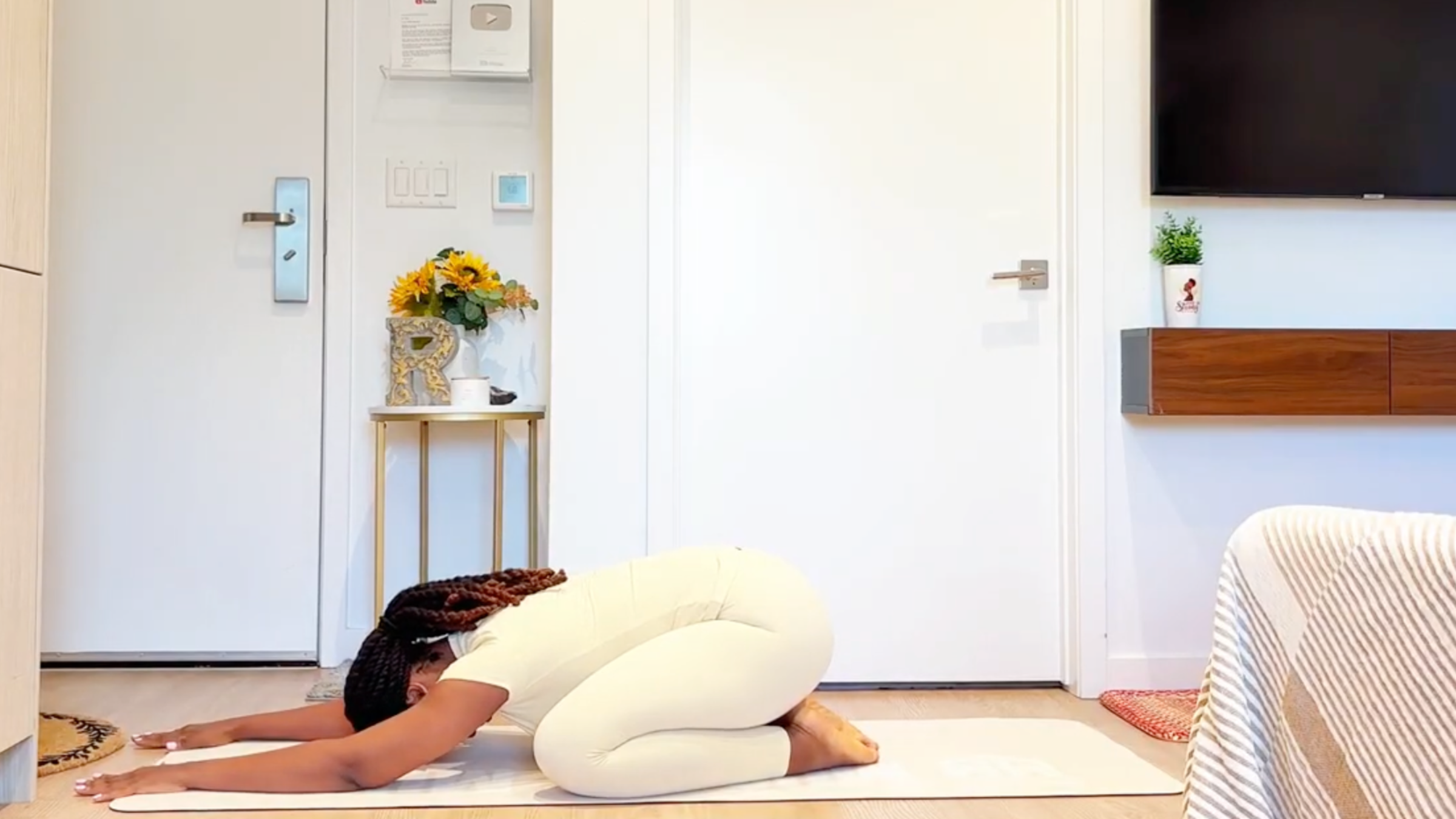 Yoga instructor Ramoni Overton doing Child’s Pose on a mat with her hips back on her heels and arms extended forward.