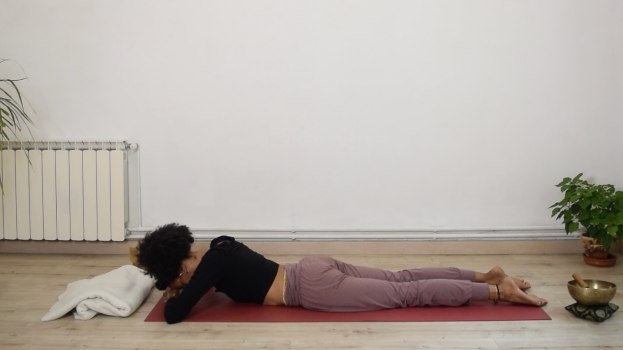 Yoga instructor Laia Bové lying prone on a yoga mat in Crocodile Pose with her forehead resting on her stacked hands.