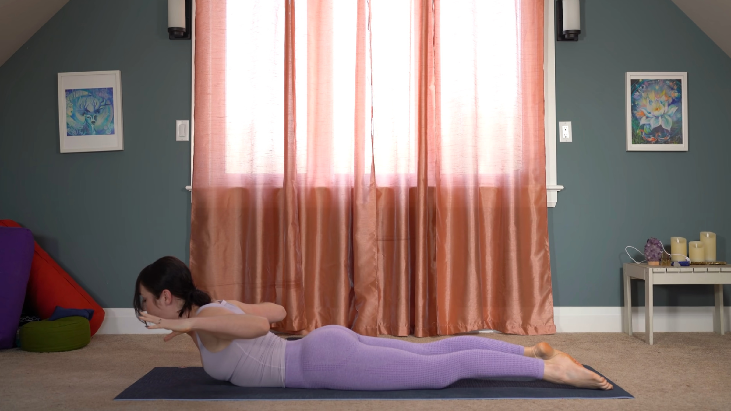 woman in purple yoga clothes lying on stomach on mat in Dynamic Cobra Pose with feet pointed, head and chest raised, and arms bent and elevated in line with shoulders