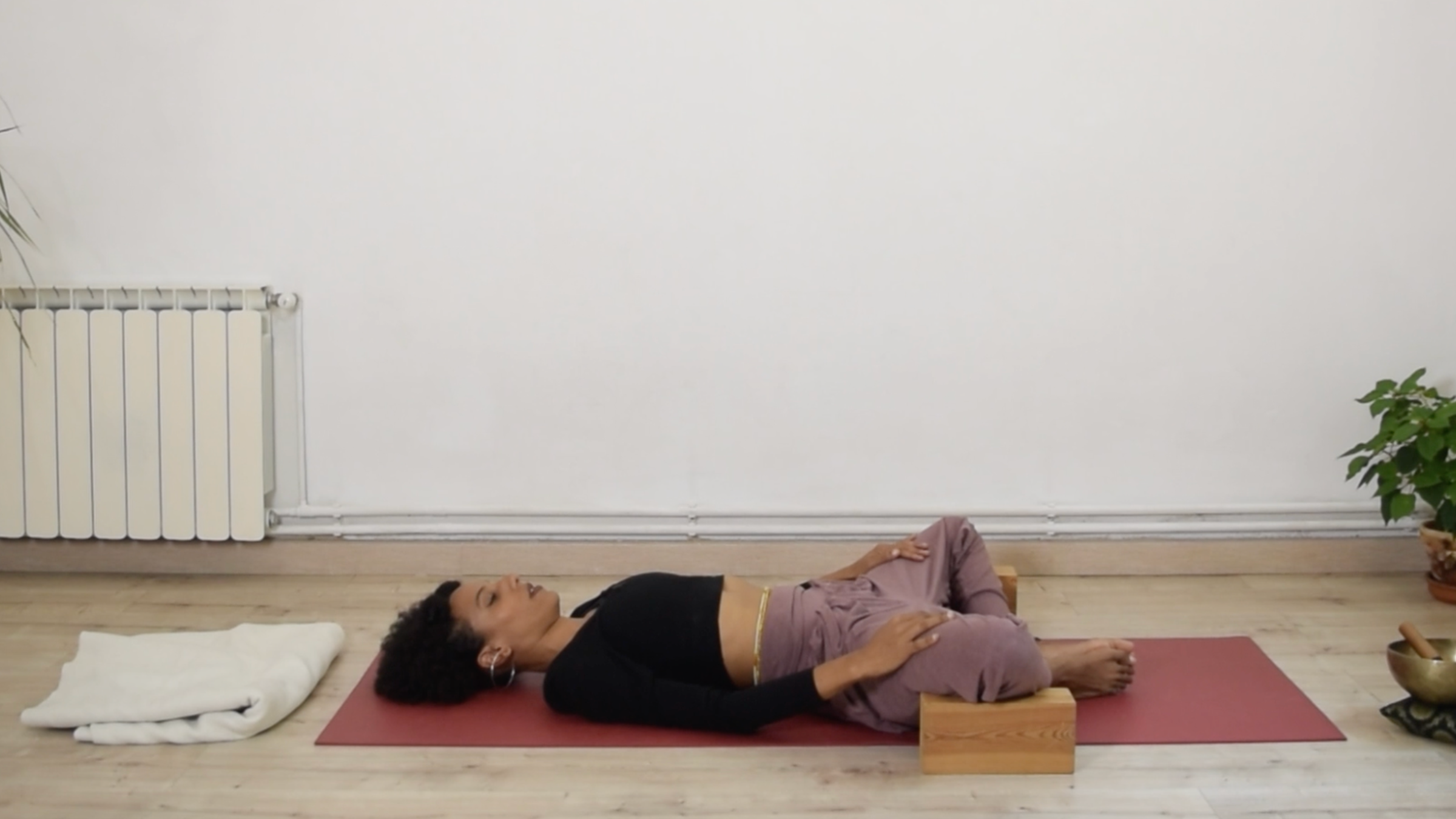 Yoga instructor Laia Bové lying on her back in Reclining Bound Angle Pose with soles of her feet together and knees opened to the sides.