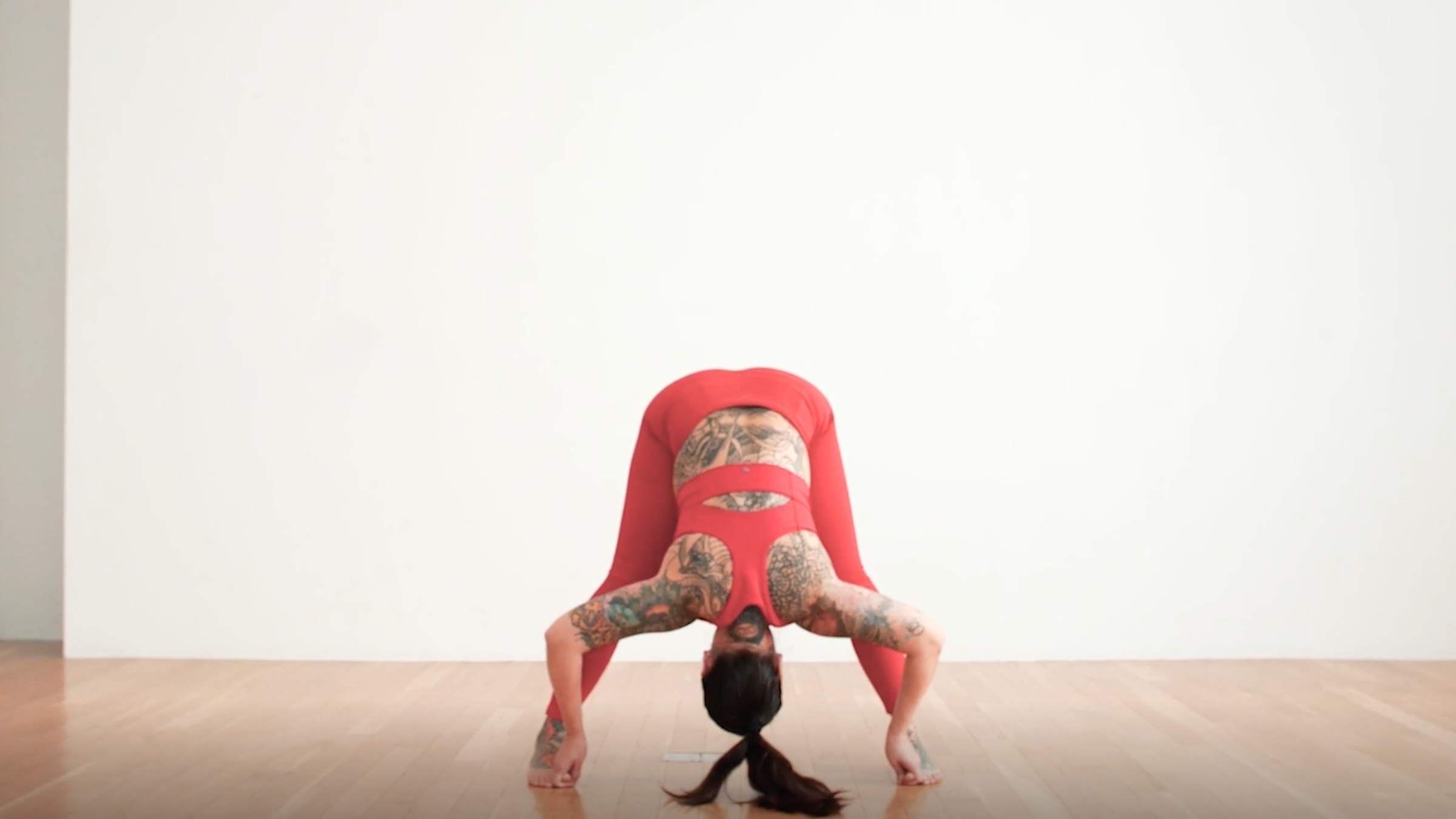 A woman in Wide-Legged Standing Forward Bend, or Prasarita Padottanasana, one of our hip mobility stretches
