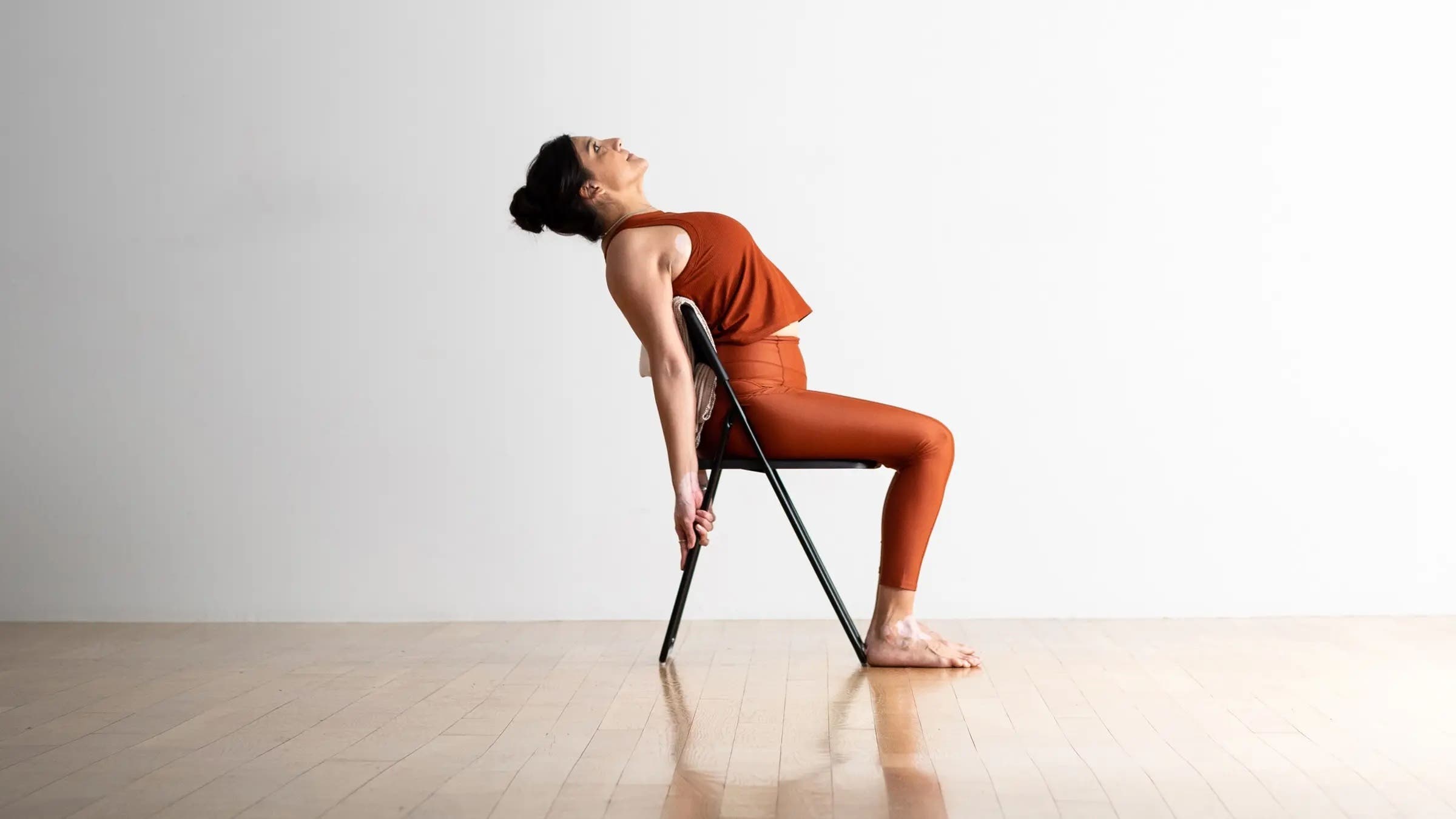 A woman in a supported version of Camel Pose, Ustrasana in Sanskrit, one of our yoga poses with props