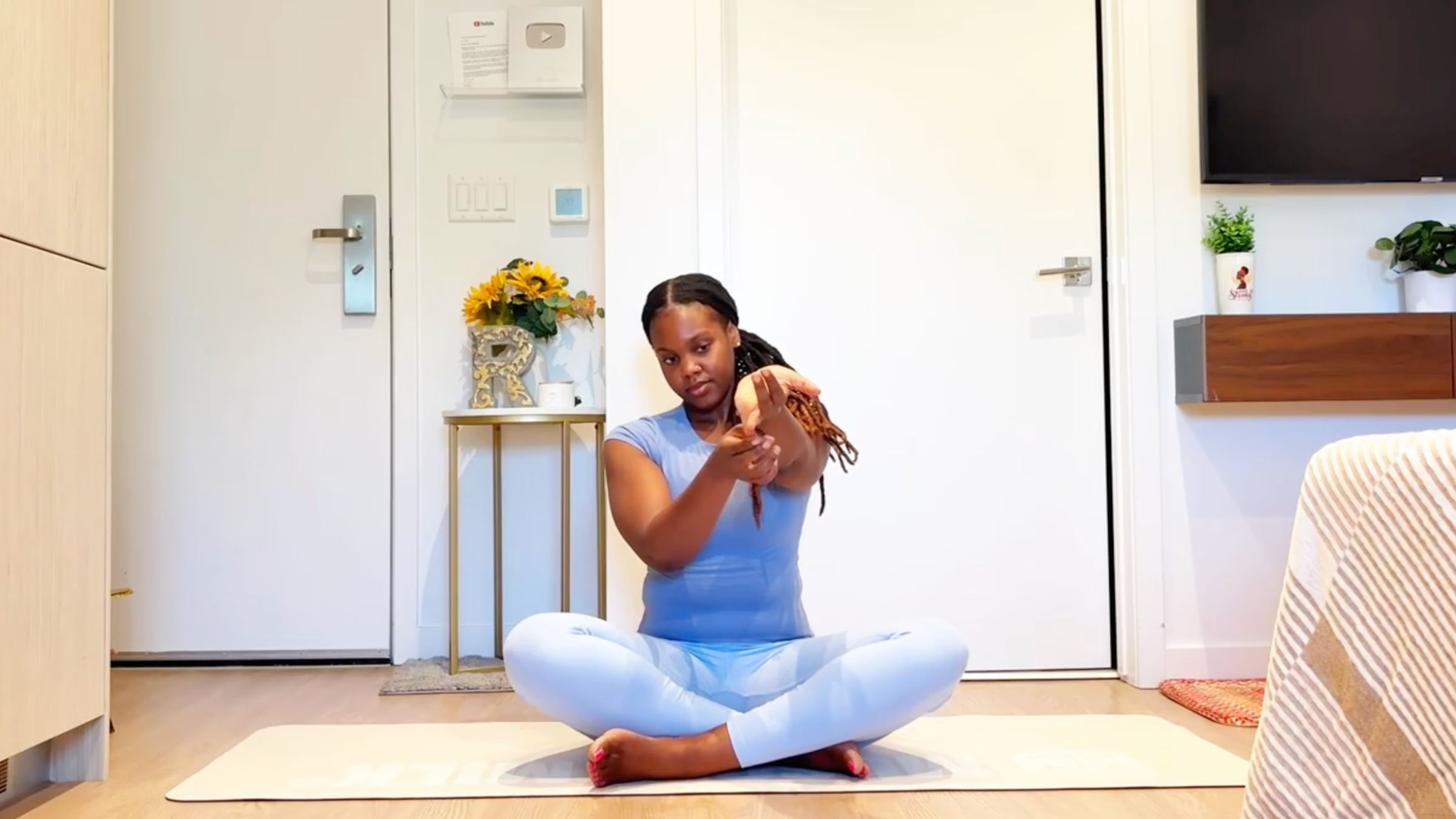 Ramoni Overton sitting on yoga mat practicing single finger stretch.