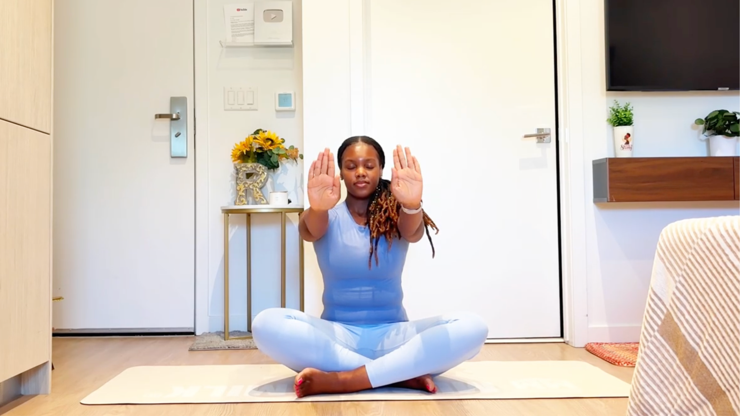 Ramoni Overton sitting on yoga mat practicing double wrist stretch.