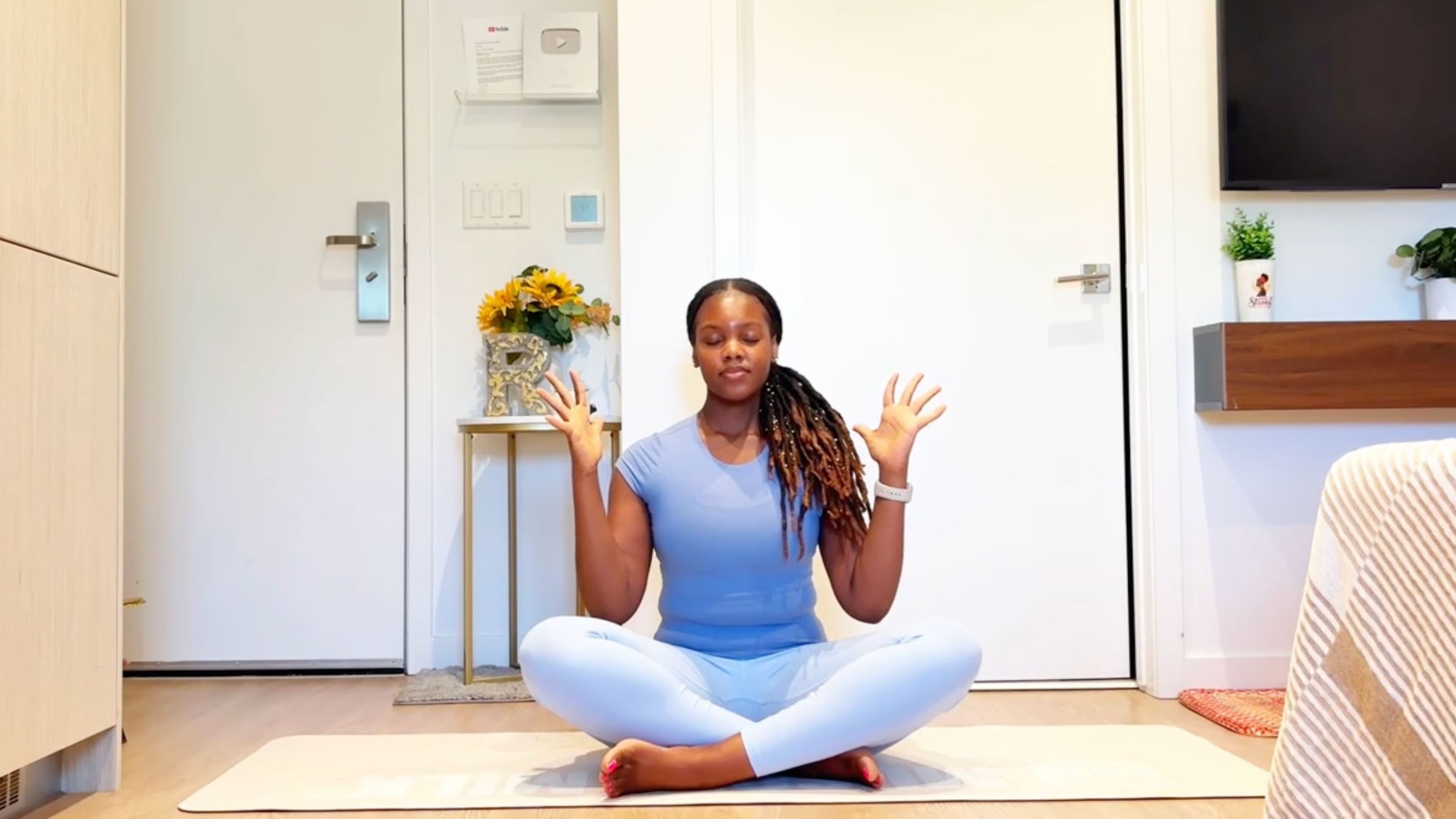 Ramoni Overton sitting on yoga mat practicing hand stretches.