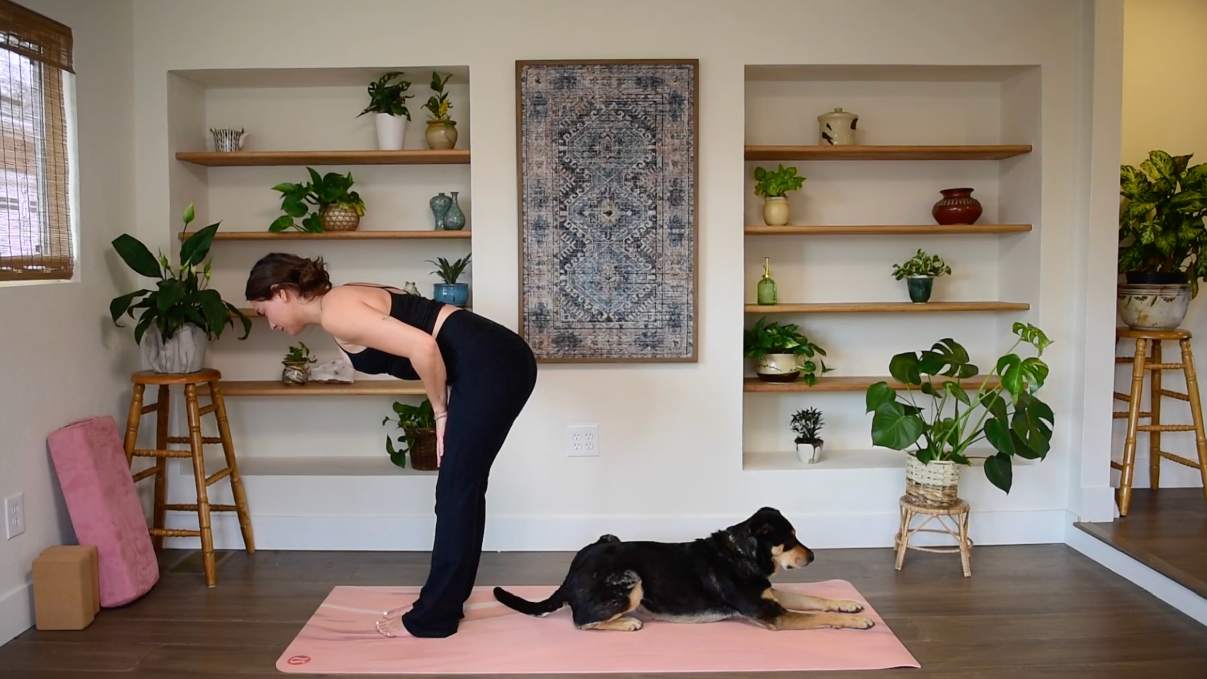 Caitlin K'eli in a half forward fold resting hands on thighs, keeping a long, flat back parallel to the yoga mat.
