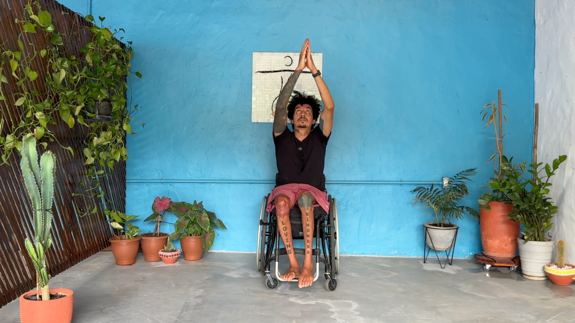 Yoga teacher leading a chair yoga class with his arms extended overhead and his gaze toward his hands
