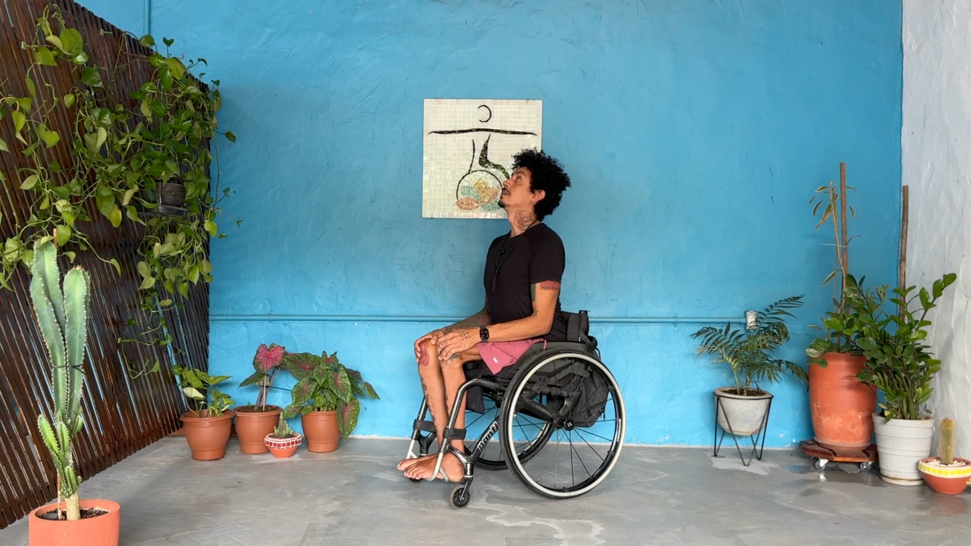 Yoga teacher seated in a wheelchair while leading class through seated Cow Pose