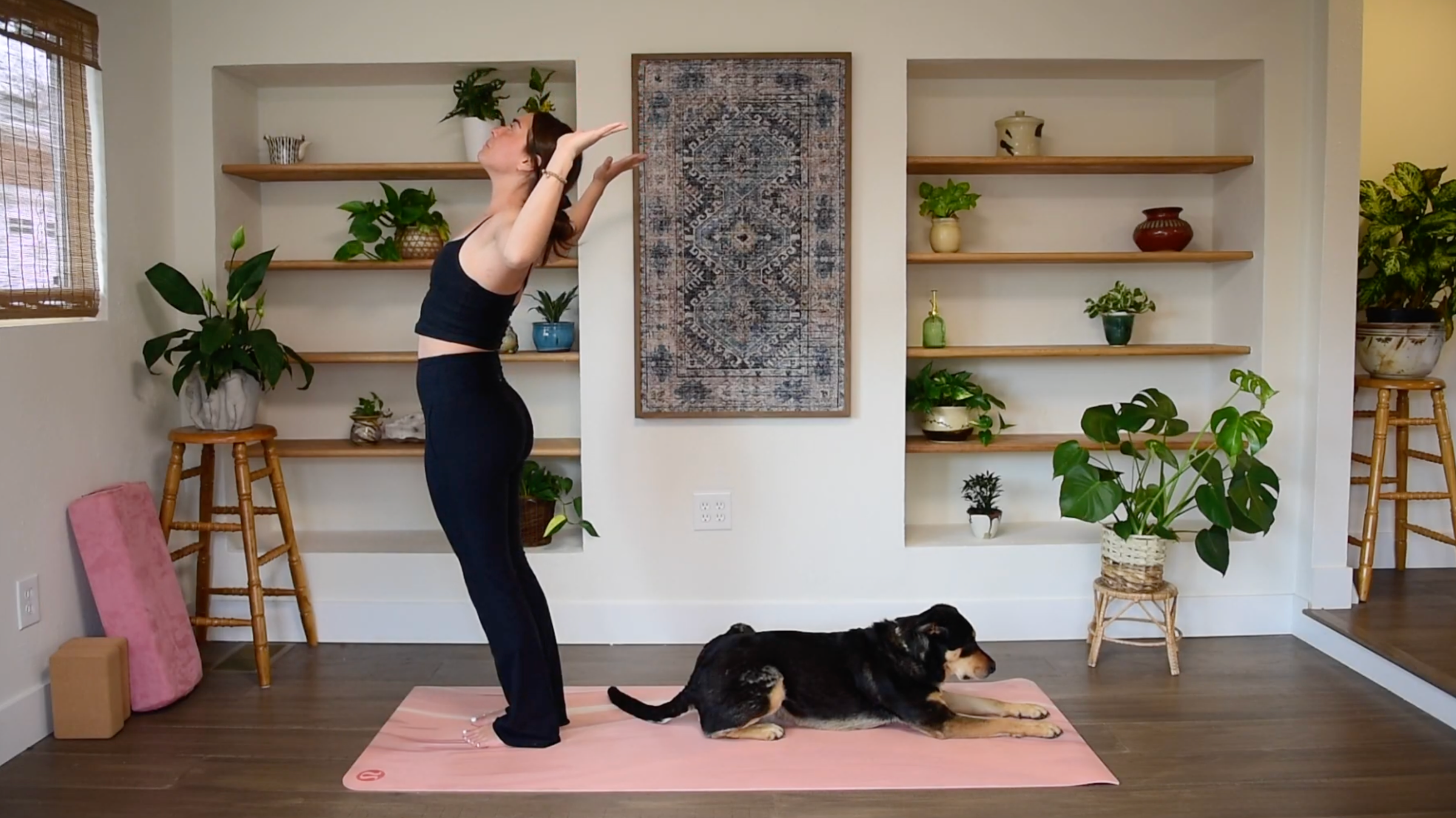 Caitlin K'eli standing on a yoga mat with elbows bent in a cactus position, arching her upper back with gaze lifted in a Baby Backbend.