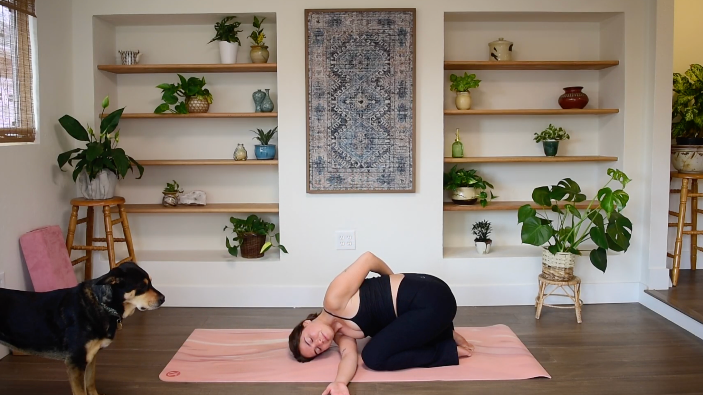 Caitlin K'eli resting in Child’s Pose, threading one arm underneath her chest across the mat in a Thread the Needle variation.