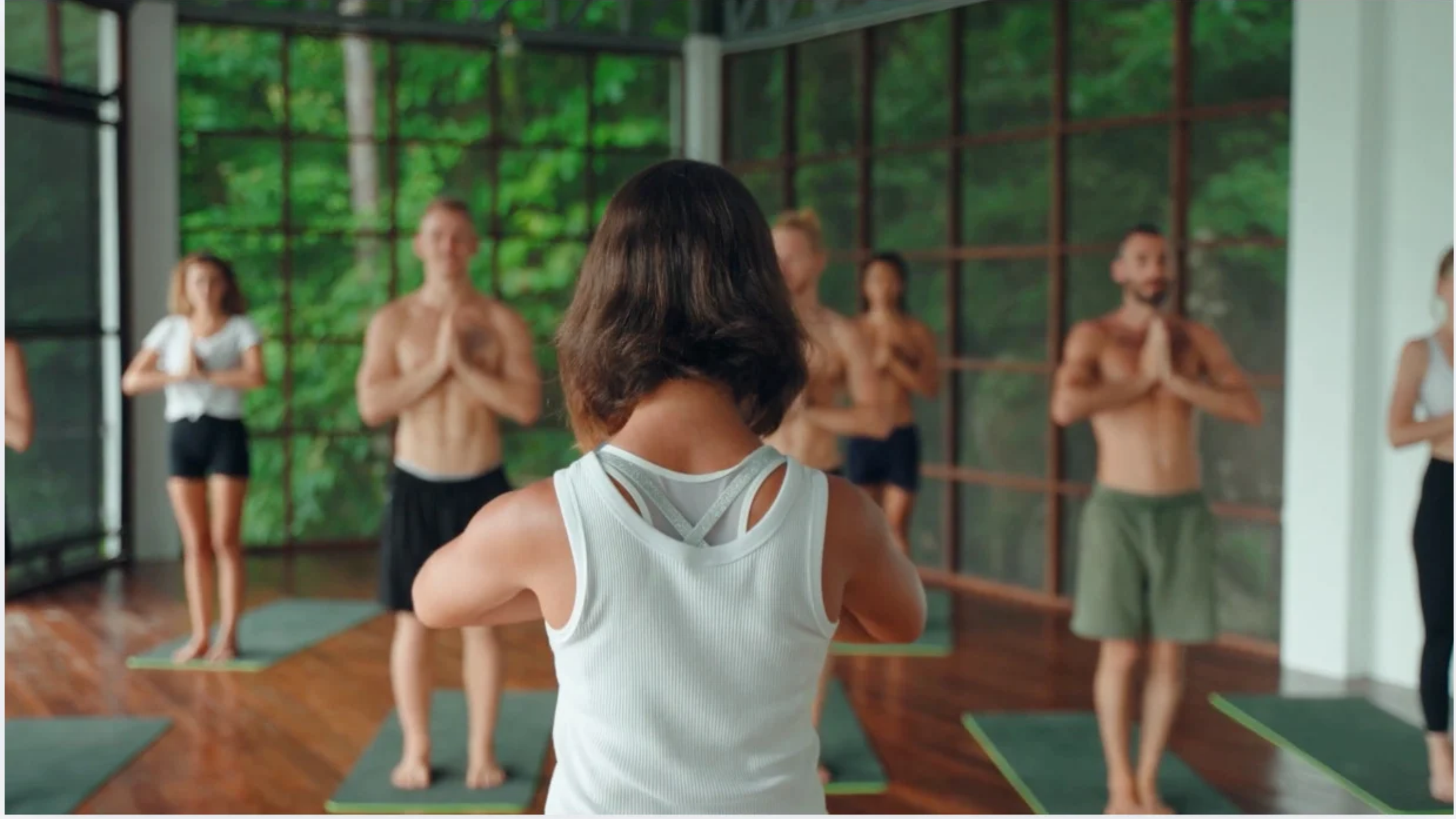 Yoga teacher overcoming nerves and teaching a class with studio windows revealing green trees in the background