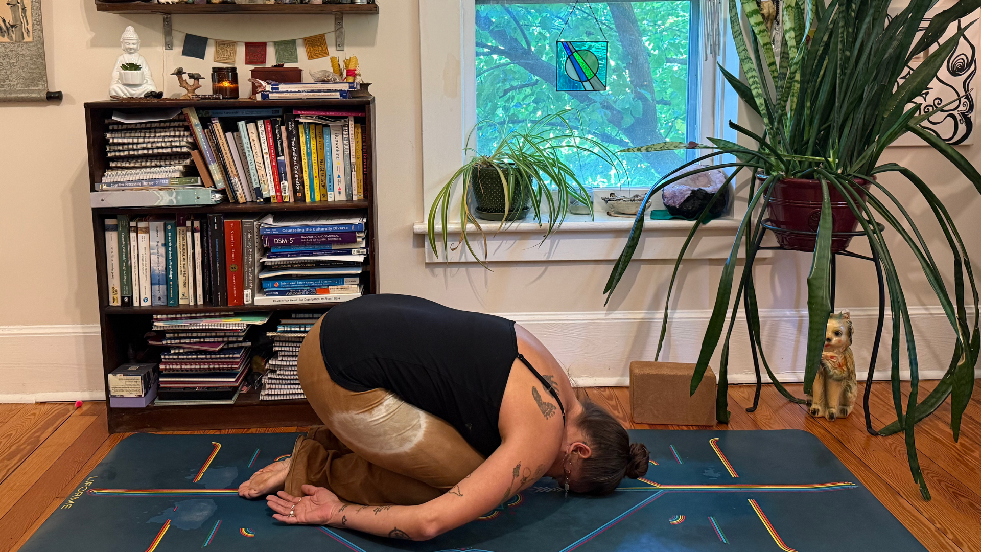 Woman kneeling on a yoga mat and leaning forward in Child's Pose