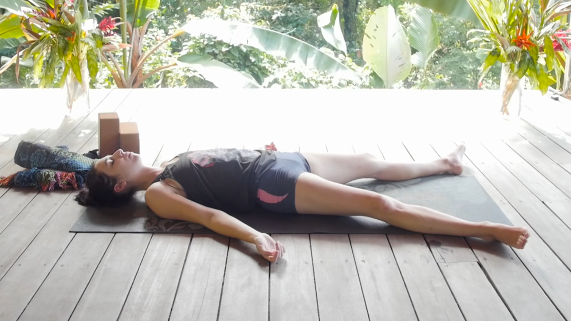 Woman lying on her back in Savasana on a yoga mat
