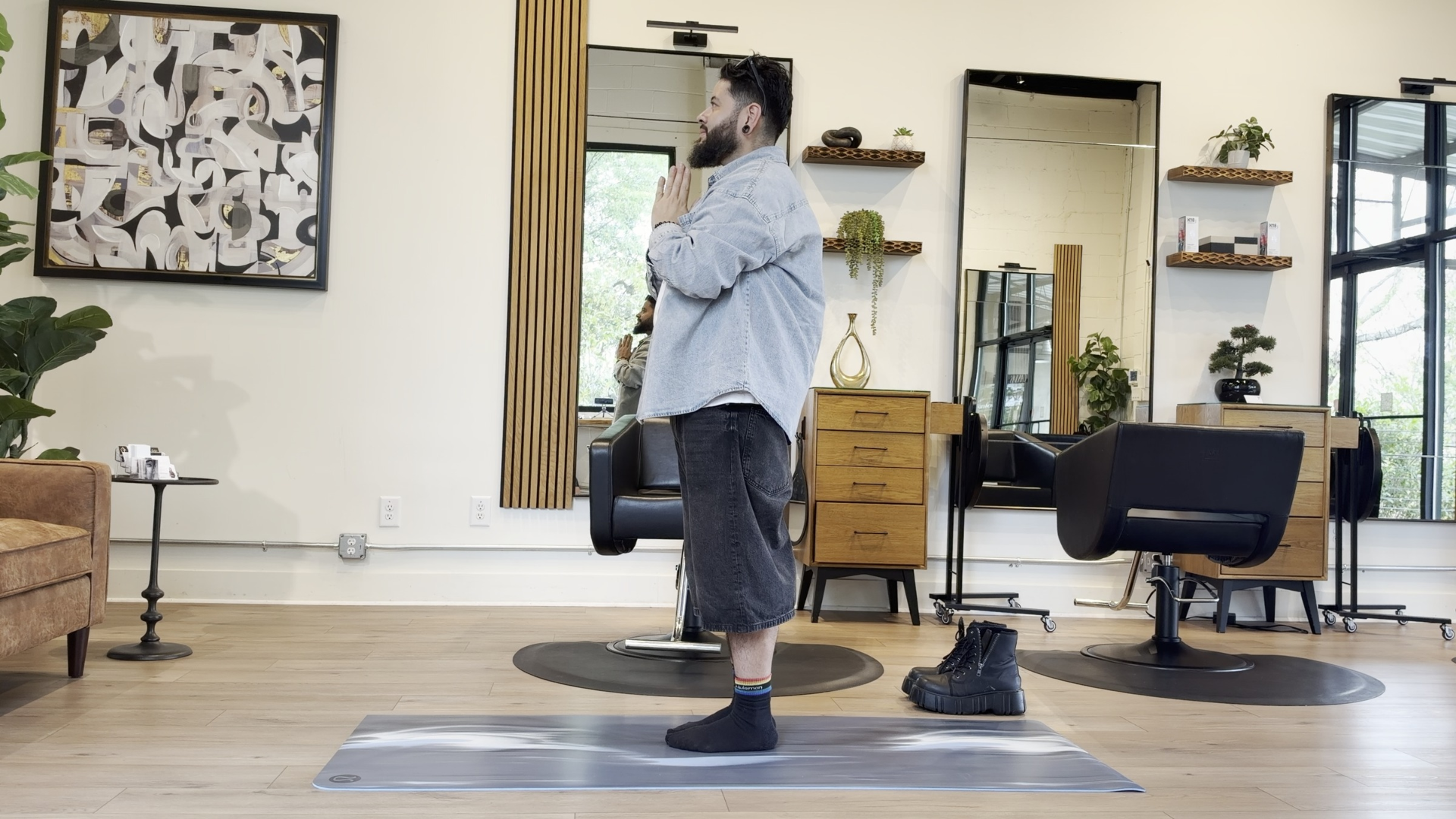 Yoga teacher standing with hands at heart on a yoga mat