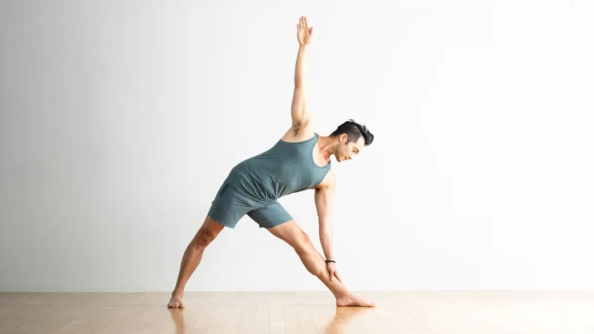 A man in Triangle Pose, Trikonasana in Sanskirt, a yoga for flexibility pose