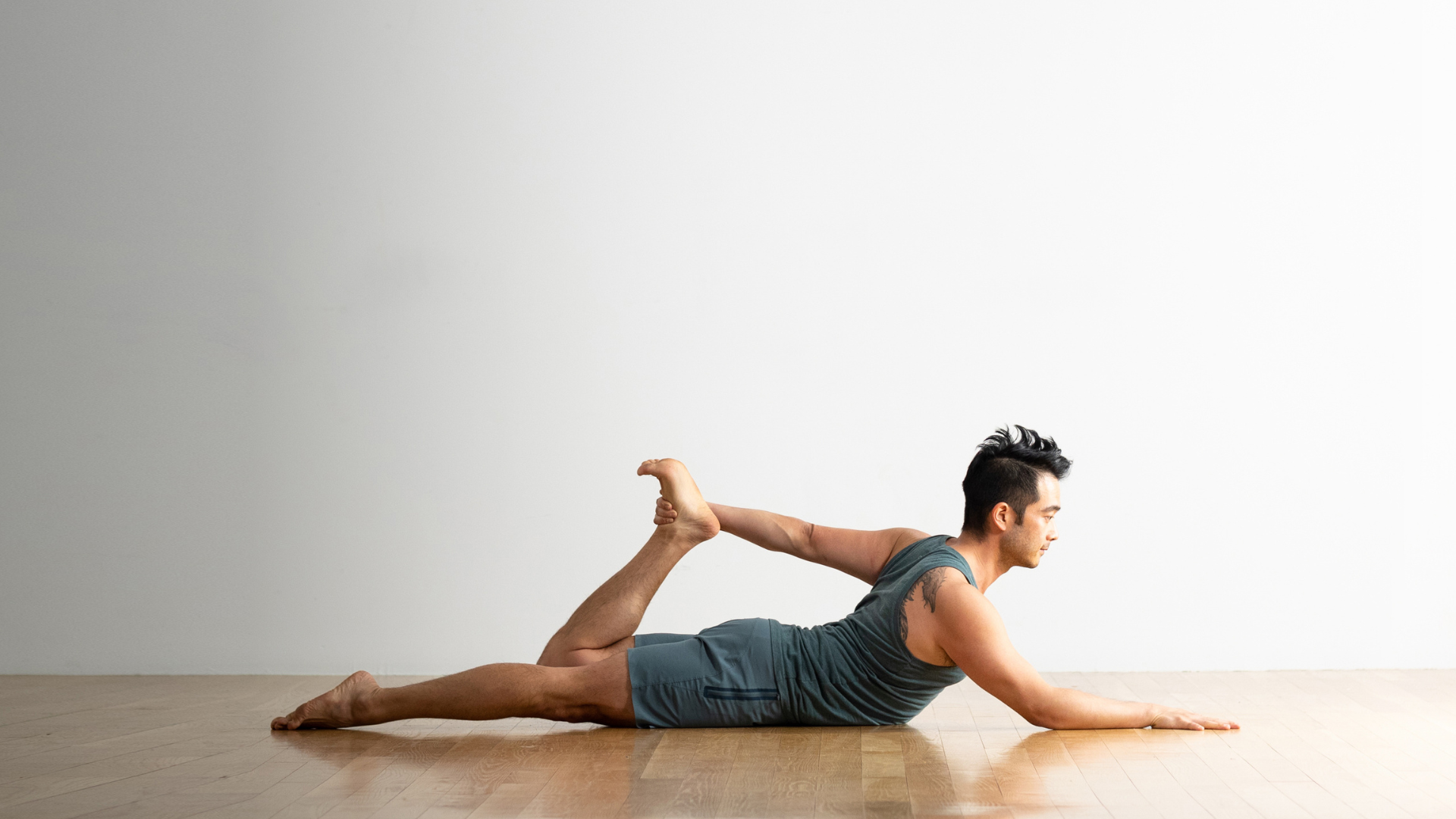 Man practicing half Bow Pose with one arm reaching back.