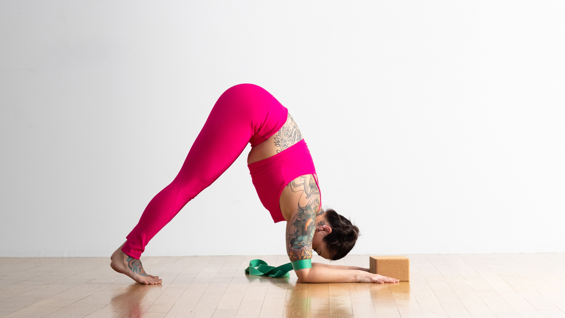 Woman practicing Dolphin Pose with a strap around her upper arms