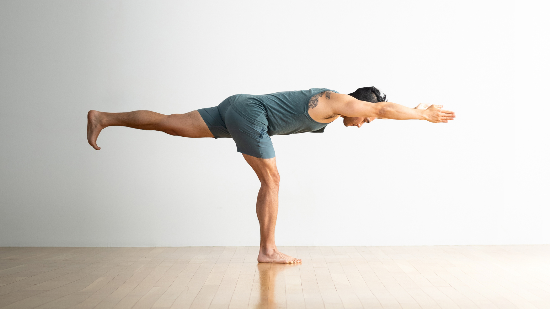 Guy practicing Warrior 3 (Virabhadrasana III) with his arms reaching alongside his ears